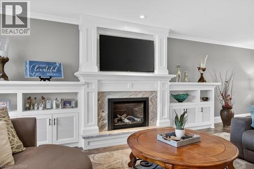 Built-in GAS fireplace with stone surround and mantle, flanked by custom cabinetry with integrated shelving and base cabinets - 25 Braemar Place, Hamilton, ON - Indoor Photo Showing Living Room With Fireplace