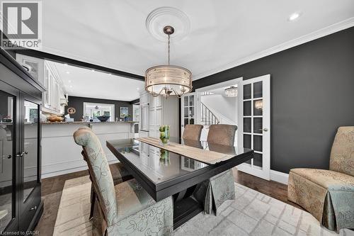 Formal dining area featuring a dark wood-finish table, a decorative chandelier, and crown molding - 25 Braemar Place, Hamilton, ON - Indoor Photo Showing Dining Room