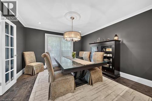 Formal dining space featuring dark wood-finish flooring, a contemporary chandelier with a ceiling medallion, and crown molding - 25 Braemar Place, Hamilton, ON - Indoor Photo Showing Dining Room
