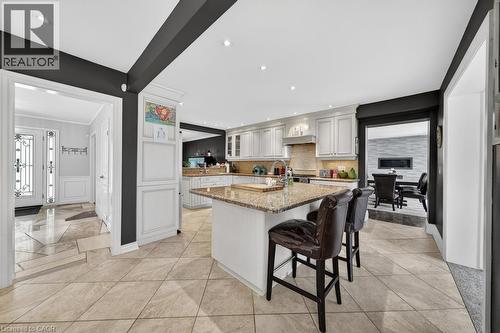 Spacious kitchen featuring an island with stone countertop, white cabinetry, integrated stainless steel appliances, recessed lighting, and tile flooring - 25 Braemar Place, Hamilton, ON - Indoor