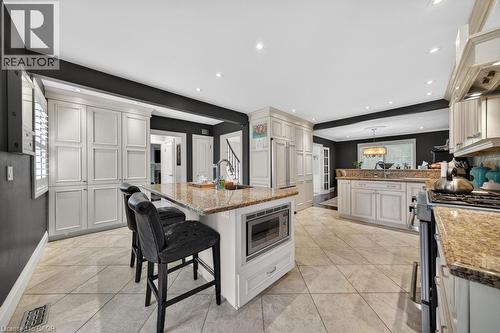 Kitchen with a central island featuring a built-in microwave, a stainless steel sink, and granite countertops - 25 Braemar Place, Hamilton, ON - Indoor Photo Showing Kitchen