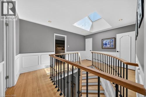 Upper-level landing featuring a prominent skylight, hardwood flooring, and wainscoting - 25 Braemar Place, Hamilton, ON - Indoor Photo Showing Other Room