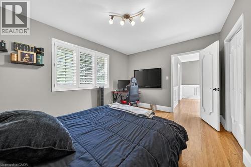 Bedroom featuring hardwood flooring, white plantation shutters, a multi-bulb track light fixture, grey wall paint, and a paneled doorway - 25 Braemar Place, Hamilton, ON - Indoor Photo Showing Bedroom
