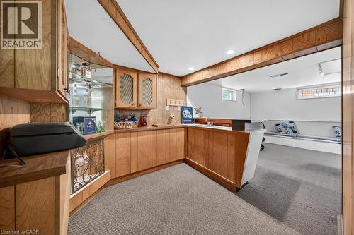 Finished lower level featuring a built-in bar with wood-finish cabinetry, a display case with glass shelving, and integrated lighting - 25 Braemar Place, Hamilton, ON - Indoor