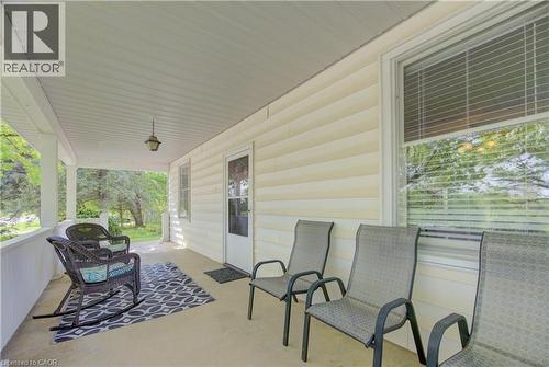 Covered front porch with light-colored siding, a white front door, and a white window frame with blinds - 1463 Kossuth Road, Cambridge, ON - Outdoor With Deck Patio Veranda With Exterior
