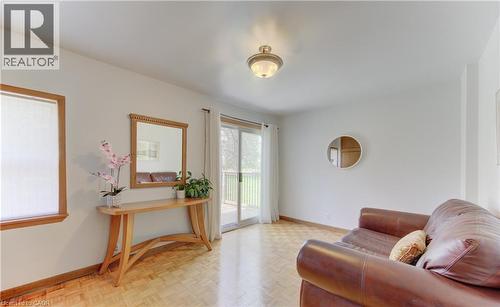Living area with wood-finish parquet flooring, white walls, and a sliding glass door leading to an outdoor deck - 1463 Kossuth Road, Cambridge, ON - Indoor