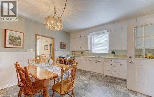 Kitchen with white upper and lower cabinetry, a window with blinds, a built-in sink, and patterned flooring - 1463 Kossuth Road, Cambridge, ON - Indoor Photo Showing Dining Room