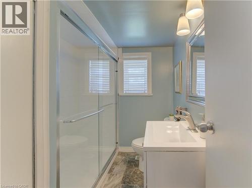 Bathroom featuring a glass-enclosed shower, white vanity with integrated sink, brushed nickel faucet, wall-mounted light fixture, and window with horizontal blinds - 1463 Kossuth Road, Cambridge, ON - Indoor Photo Showing Bathroom
