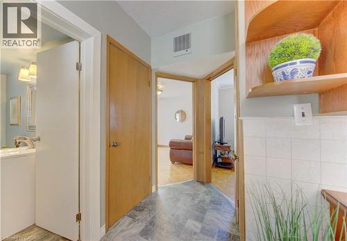Interior hallway featuring wood-finish doors, a built-in wood-finish shelving unit, and grey-toned floor tile - 1463 Kossuth Road, Cambridge, ON - Indoor Photo Showing Other Room