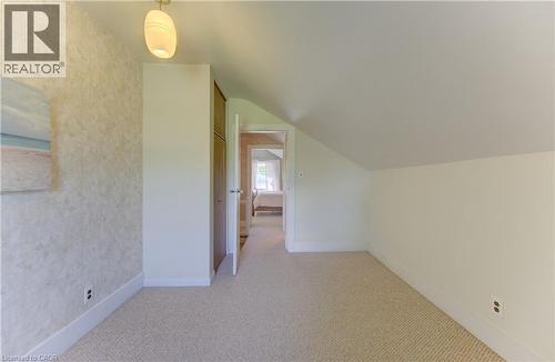 Carpeted room featuring a sloped ceiling, built-in cabinetry with wood-finish doors, and a decorative wall finish - 1463 Kossuth Road, Cambridge, ON - Indoor Photo Showing Other Room
