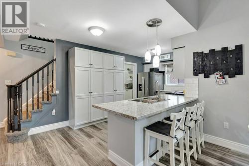 Kitchen area featuring wood-finish flooring, a kitchen island with a light-toned countertop, a stainless steel sink with a gooseneck faucet, and pendant lighting - 49 Small Court, Cambridge, ON - Indoor Photo Showing Kitchen With Double Sink With Upgraded Kitchen