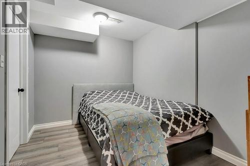 Bedroom featuring light gray walls, wood-finish flooring, white trim, and a contemporary ceiling light fixture - 49 Small Court, Cambridge, ON - Indoor Photo Showing Bedroom