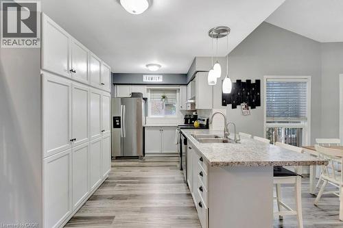Spacious kitchen featuring extensive white cabinetry, stainless steel appliances, a large island with a stone-finish countertop, and wood-finish flooring - 49 Small Court, Cambridge, ON - Indoor Photo Showing Kitchen With Double Sink With Upgraded Kitchen