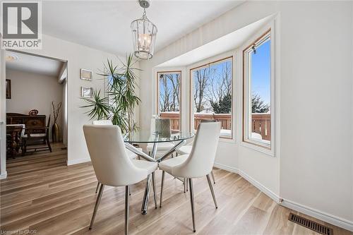 Bay window with multiple panes of glass, a contemporary ceiling light fixture, wood-finish flooring, white baseboards, and a doorway opening to an additional room - 488 Heather Hill Place, Waterloo, ON - Indoor Photo Showing Dining Room