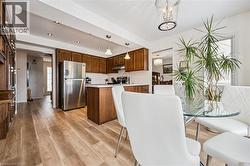 Open-concept kitchen and dining area featuring wood-finish flooring, recessed lighting, and a stainless steel refrigerator - 