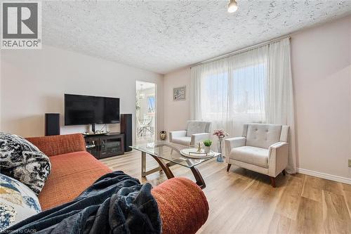 Living area featuring wood-finish flooring, a large window with sheer drapery, and a textured ceiling - 488 Heather Hill Place, Waterloo, ON - Indoor Photo Showing Living Room