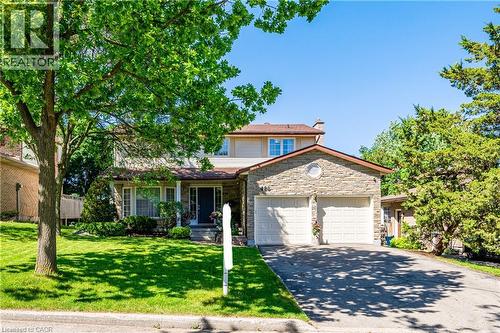 Stone-front residence featuring a two-car garage, mature front yard landscaping, paved driveway, and a covered entry - 488 Heather Hill Place, Waterloo, ON - Outdoor