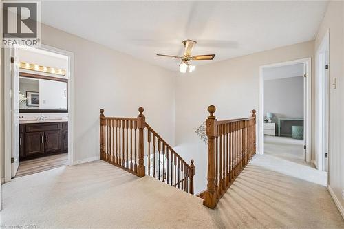 Upper-level landing featuring light-toned carpeting, a traditional wood-finish banister, and a ceiling fan with integrated lighting - 488 Heather Hill Place, Waterloo, ON - Indoor Photo Showing Other Room