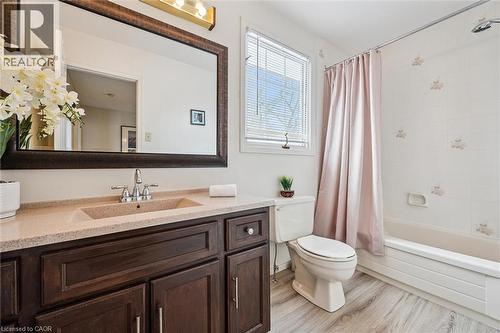 Bathroom featuring a dark wood-finish vanity with an integrated sink and light-toned countertop, a large framed mirror, a window with blinds, and wood-finish flooring - 488 Heather Hill Place, Waterloo, ON - Indoor Photo Showing Bathroom