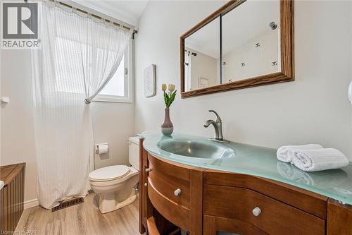 Bathroom featuring a wood-finish vanity with a curved translucent countertop and integrated sink - 488 Heather Hill Place, Waterloo, ON - Indoor Photo Showing Bathroom