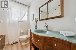 Bathroom featuring a wood-finish vanity with a curved translucent countertop and integrated sink - 
