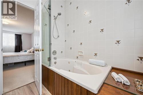 Jetted soaking tub with a glass shower enclosure and a wood-finish surround - 488 Heather Hill Place, Waterloo, ON - Indoor Photo Showing Bathroom
