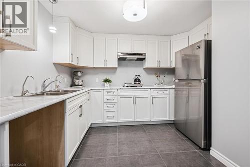 L-shaped kitchen featuring white cabinetry, stainless steel appliances, a double basin sink, and dark tile flooring - 488 Heather Hill Place, Waterloo, ON - Indoor Photo Showing Kitchen With Double Sink