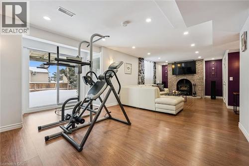 Finished lower level featuring wood-finish flooring, recessed lighting, and a prominent brick fireplace - 488 Heather Hill Place, Waterloo, ON - Indoor Photo Showing Gym Room