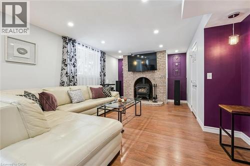 Living area featuring wood-finish flooring, recessed ceiling lighting, and a brick-surround fireplace with an arched opening - 488 Heather Hill Place, Waterloo, ON - Indoor Photo Showing Living Room With Fireplace