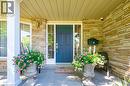 Inviting front entry featuring a deep blue door with sidelights, stacked stone facade, sheltered porch, and a column accent - 488 Heather Hill Place, Waterloo, ON  - Outdoor With Deck Patio Veranda With Exterior 