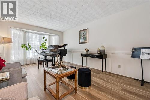 Spacious living area featuring wood-finish flooring, a prominent bay window, and crisp white walls with wainscoting - 488 Heather Hill Place, Waterloo, ON - Indoor Photo Showing Living Room