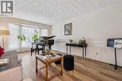 Spacious living area featuring wood-finish flooring, a prominent bay window, and crisp white walls with wainscoting - 