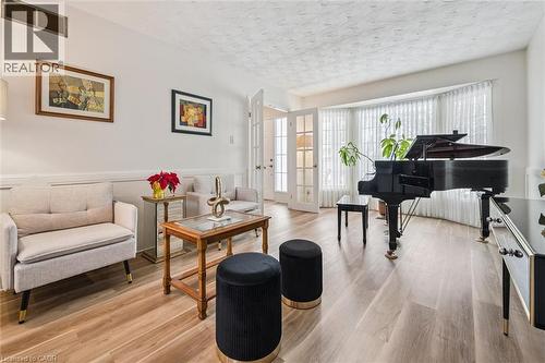 Spacious room featuring light wood-finish flooring, white walls with decorative chair rail molding, and a bay window with vertical blinds - 488 Heather Hill Place, Waterloo, ON - Indoor Photo Showing Living Room