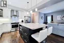 Modern kitchen featuring a large island with a light-toned countertop, white cabinetry with silver hardware, stainless steel appliances, and wood-finish flooring - 