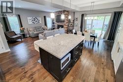 Kitchen island featuring a light-toned countertop, dark cabinetry, and integrated microwave - 