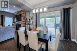 Dining area featuring dark wood-finish flooring, a contemporary linear chandelier, and direct access to an outdoor deck via sliding glass doors - 