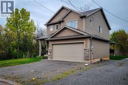 Two-story exterior featuring siding and stone accents, an attached garage, and a gravel driveway - 