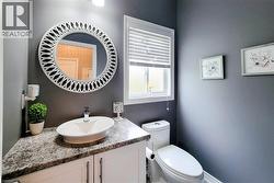 Bathroom featuring a vessel sink, speckled countertop, and white cabinetry - 