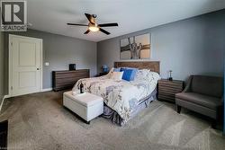 Carpeted bedroom featuring a ceiling fan with integrated lighting, a paneled interior door, and a built-in headboard - 