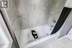 Bathtub with full-height subway tile surround, chrome fixtures, and coordinating tile flooring - 