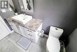Bathroom featuring a white vanity with brushed nickel hardware, a vessel sink, and a speckled countertop - 