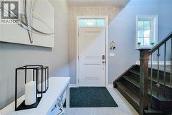 Entryway featuring a paneled door with transom window, wood-finish flooring, and a dark wood staircase with wrought iron balusters - 