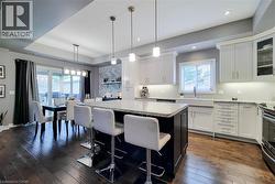 Spacious kitchen featuring an expansive center island with seating, a farmhouse sink, white cabinetry with under-cabinet lighting, and stainless-steel appliances - 