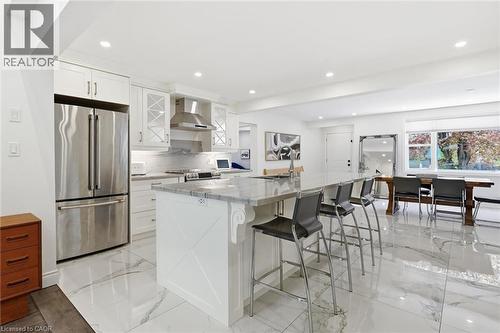 Open-concept kitchen featuring white shaker cabinetry, stainless steel appliances, a large island with seating, and polished marble-look flooring - 24 Glenwood Crescent, Hamilton, ON - Indoor Photo Showing Kitchen With Upgraded Kitchen