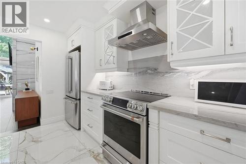 Bright kitchen featuring white cabinetry, integrated stainless steel appliances, and sleek stone countertops - 24 Glenwood Crescent, Hamilton, ON - Indoor Photo Showing Kitchen