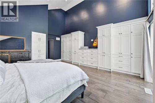 Vaulted ceilings highlight a wall of custom white built-in cabinetry and drawers, providing extensive storage solutions - 24 Glenwood Crescent, Hamilton, ON - Indoor Photo Showing Bedroom