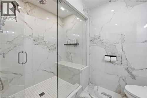 Spacious shower enclosure featuring full-height veined tile, a built-in shower bench, and a rain showerhead - 24 Glenwood Crescent, Hamilton, ON - Indoor Photo Showing Bathroom