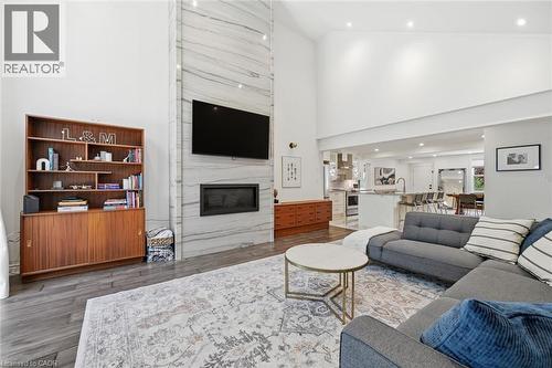 Vaulted ceilings enhance this living area featuring a floor-to-ceiling stone-clad fireplace with an integrated linear firebox - 24 Glenwood Crescent, Hamilton, ON - Indoor Photo Showing Living Room With Fireplace