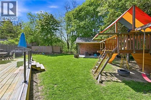 Expansive backyard featuring a wood deck with glass railing, a green lawn, and mature trees - 24 Glenwood Crescent, Hamilton, ON - Outdoor With Deck Patio Veranda
