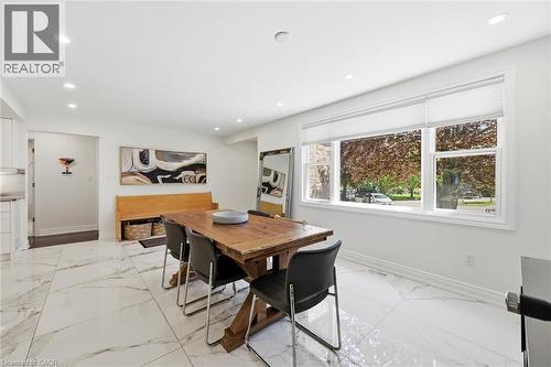 Dining area featuring large format white tile flooring with grey veining, a substantial wood dining table, and a wide window with a white frame - 24 Glenwood Crescent, Hamilton, ON - Indoor